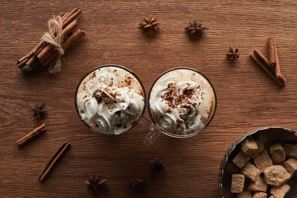 Top view of Christmas cacao with whipped cream on wooden table with anise, brown sugar and cinnamon — Stock Photo