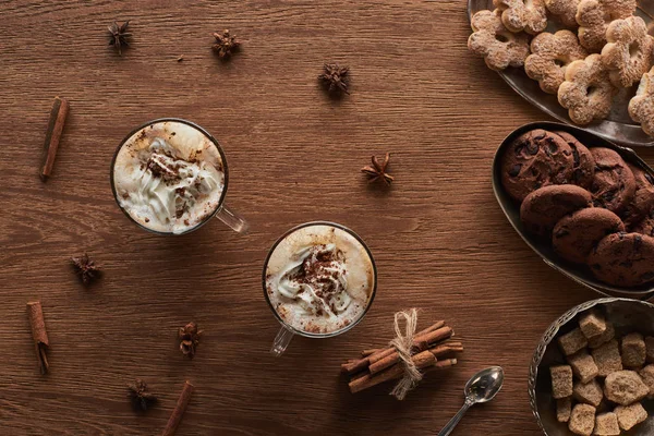 Weihnachtskakao mit Schlagsahne auf Holztisch mit Gewürzen und Plätzchen — Stockfoto