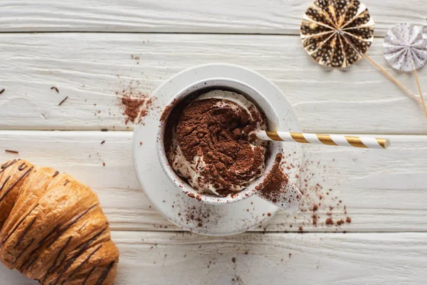 Vista superior del cacao de Navidad en taza con decoración cerca de croissant en mesa de madera blanca - foto de stock