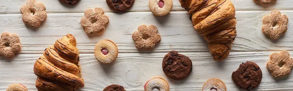 Draufsicht auf süße Kekse und Croissants auf weißem Holztisch, Panoramaaufnahme — Stockfoto