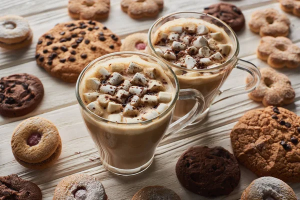 Cacao con marshmallow in tazze vicino ai biscotti sul tavolo di legno bianco — Foto stock