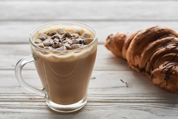 Kakao mit Marshmallow in Tasse neben Croissant auf weißem Holztisch — Stockfoto