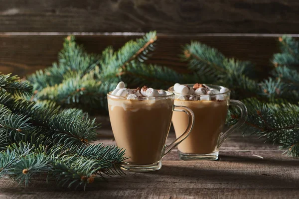 Selective focus of cacao with marshmallow and cacao powder in mugs near pine branches on wooden table — Stock Photo