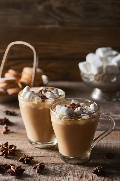 Cacao with marshmallow in mugs near anise on wooden table — Stock Photo