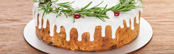 Рождественский пирог с глазурью, розмарином и клюквой на деревянном столе — стоковое фото