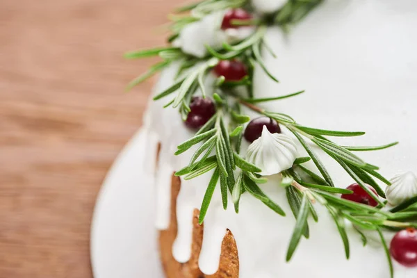 Christmas pie with white icing, rosemary and cranberries on wooden table — Stock Photo