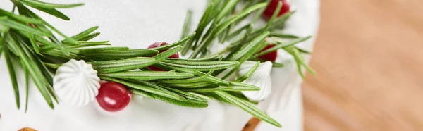 Close up of christmas cake with white glaze, rosemary and cranberries on wooden table — Stock Photo