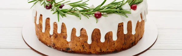 Christmas pie with white icing and rosemary on plate on wooden table — Stock Photo