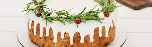 Праздничный рождественский пирог с белой глазурью, розмарином и клюквой на деревянном столе — стоковое фото