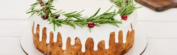 Festive christmas pie with white icing, rosemary and cranberries on wooden table — Stock Photo