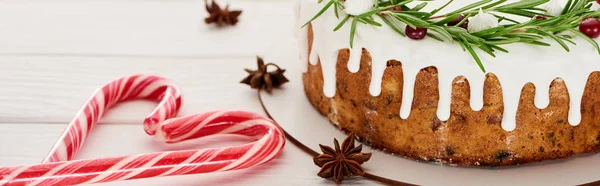 Christmas pie with icing on white wooden table with candy canes and anise star seeds — Stock Photo