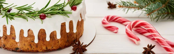 Torta de Natal doce com cobertura em mesa de madeira branca com bengalas doces e ramos de abeto — Fotografia de Stock