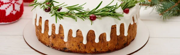 Різдвяний пиріг з білим глазур'ю, розмарином і журавлиною на білому дерев'яному столі з ялиновими гілками — стокове фото