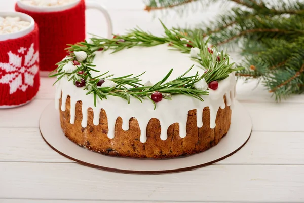 Tarte de Noël sucrée avec glaçage et deux tasses de cacao avec guimauves sur table en bois blanc — Photo de stock