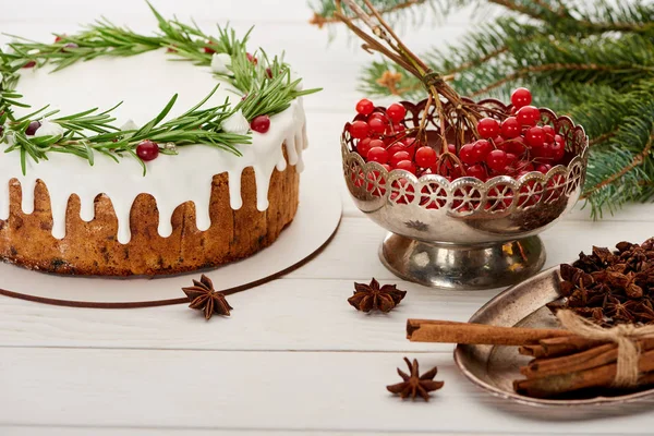 Pastel de Navidad, especias y bayas viburnum en la mesa de madera blanca con ramas de abeto - foto de stock