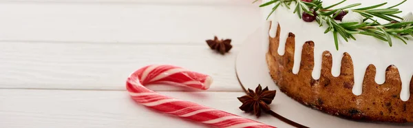 Christmas pie with icing on white wooden table with candy canes and anise star seeds — Stock Photo