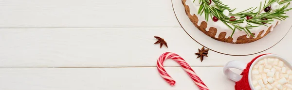Weihnachtskuchen von oben auf weißem Holztisch mit Zuckerrohr und Tasse Kakao mit Marshmallows — Stockfoto