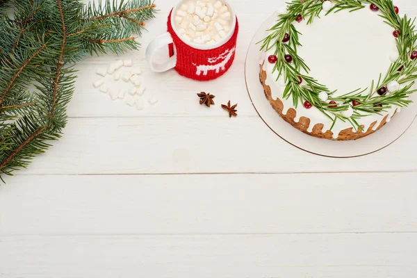 Top view of christmas pie on white wooden table with cup of cocoa with marshmallows and spruce branches — Stock Photo