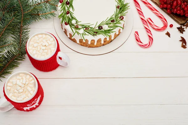 Top view of two cups of cocoa with marshmallows and christmas pie with icing on white wooden table — Stock Photo