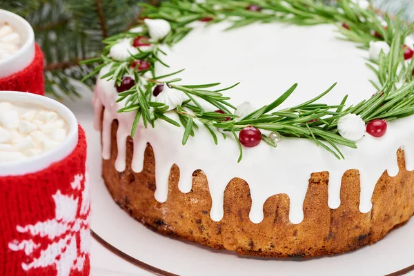 Nahaufnahme von Weihnachtskuchen mit Zuckerguss auf weißem Holztisch mit Tassen Kakao — Stockfoto