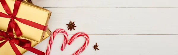 Vista superior de las cajas de regalo de Navidad y bastones de caramelo en la mesa de madera blanca - foto de stock