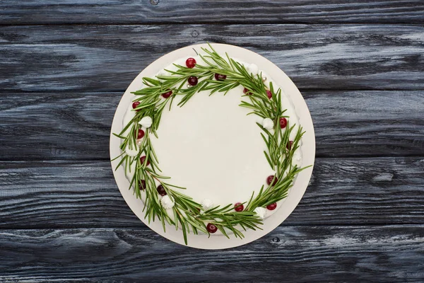 Vista superior da torta de Natal tradicional com glacê branco, alecrim e cranberries na mesa de madeira escura — Fotografia de Stock