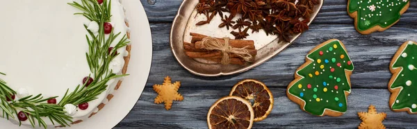 Vista superior del pastel de Navidad, especias y galletas de árbol de Navidad en la mesa de madera oscura - foto de stock