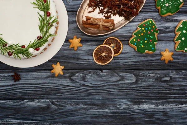 Ansicht von Weihnachtskuchen, Gewürzen und Plätzchen auf dunklem Holztisch — Stockfoto