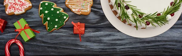 Vue du dessus de tarte de Noël, petits cadeaux et biscuits sur table en bois sombre — Photo de stock