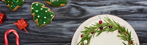 Vista superior da torta de Natal, bengalas doces, presentes e biscoitos na mesa de madeira escura — Fotografia de Stock