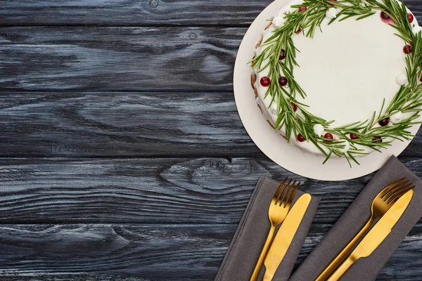 Vista superior de pastel de Navidad con tenedores y cuchillos en servilletas en mesa de madera oscura — Stock Photo