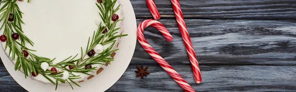 Vista dall'alto della torta di Natale con rosmarino e mirtilli rossi su tavolo di legno scuro con bastoncini di zucchero — Foto stock