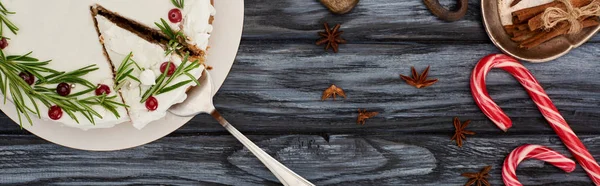 Vista superior da torta de Natal com alecrim e cranberries na mesa de madeira escura com bastões de doces e staranise — Fotografia de Stock