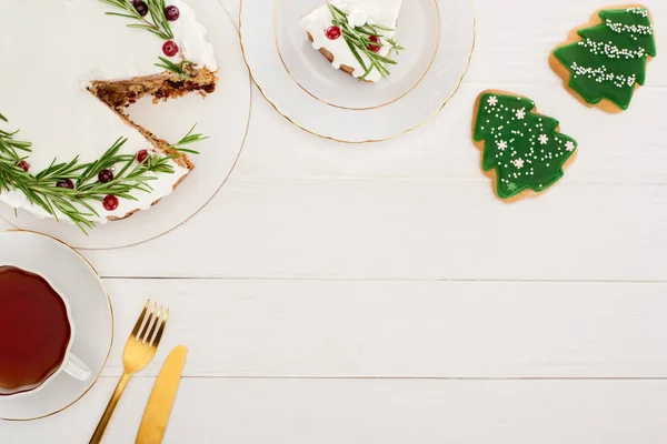 Ansicht von Weihnachtskuchen, Tee, Plätzchen, Gabel und Messer auf weißem Holztisch — Stockfoto