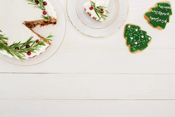 Vista superior da torta de Natal e biscoitos de árvore de Natal na mesa de madeira branca — Fotografia de Stock