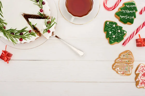 Vista superior da torta de Natal, xícara de chá e biscoitos de árvore de natal na mesa de madeira branca — Fotografia de Stock