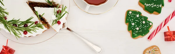 Blick von oben auf Weihnachtskuchen, Tasse Tee und Christbaumkekse auf weißem Holztisch — Stockfoto