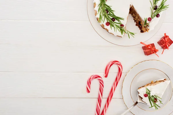 Vista superior da torta de Natal com alecrim e cranberries na mesa de madeira branca com bastões de doces e pequenos presentes — Fotografia de Stock