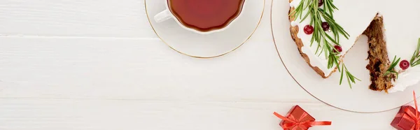 Draufsicht auf Weihnachtskuchen mit Rosmarin und Preiselbeeren auf weißem Holztisch mit Tasse Tee kleine Geschenke — Stockfoto