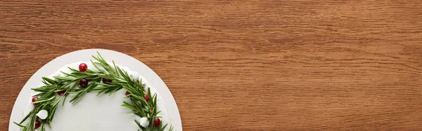 Top view of christmas pie with white icing, rosemary and cranberries on wooden table — Stock Photo