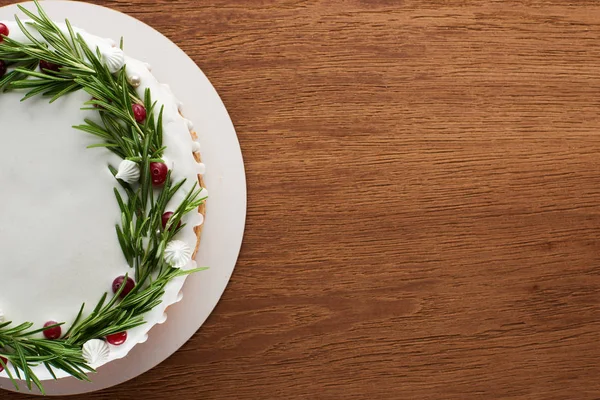 Top view of traditional christmas pie with icing, rosemary and cranberries on wooden table — Stock Photo