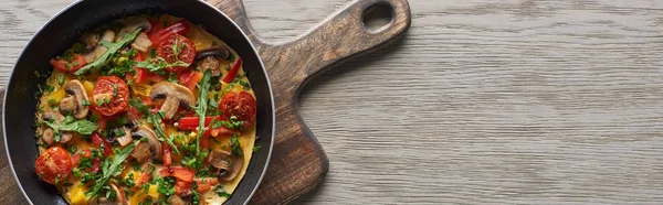 Top view of homemade omelet for breakfast in frying pan on wooden board — Stock Photo