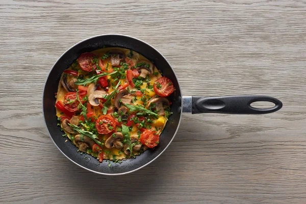 Top view of delicious homemade omelet in frying pan on wooden table — Stock Photo