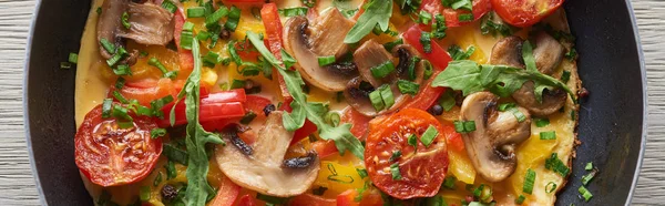 Blick von oben auf hausgemachtes Omelett mit Pilzen, Tomaten und Gemüse in der Pfanne — Stockfoto