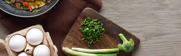 Vue du dessus de l'omelette dans une poêle avec des œufs et des légumes sur une table en bois — Photo de stock