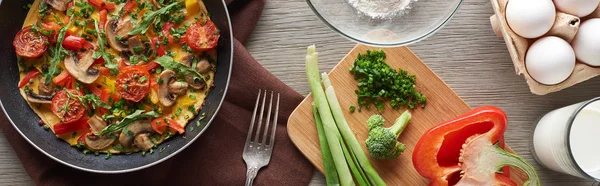 Top view of delicious homemade omelet in frying pan with ingredients on table — Stock Photo