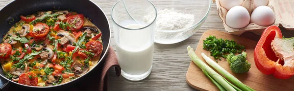 Homemade omelet in frying pan with milk, flour, eggs and broccoli on table — Stock Photo