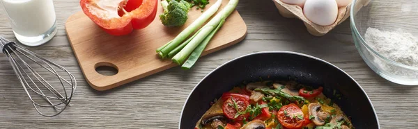 Leckeres hausgemachtes Omelett in der Pfanne mit Zutaten auf dem Tisch — Stockfoto