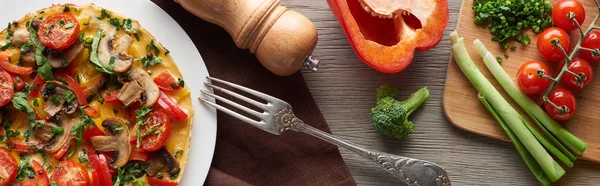 Top view of delicious omelet for breakfast on wooden table with ingredients and fork — Stock Photo