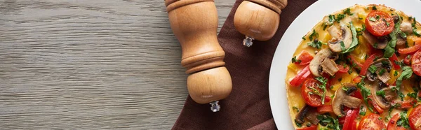 Vista superior de omelete caseiro com legumes em mesa de madeira com pimenta e sal — Fotografia de Stock